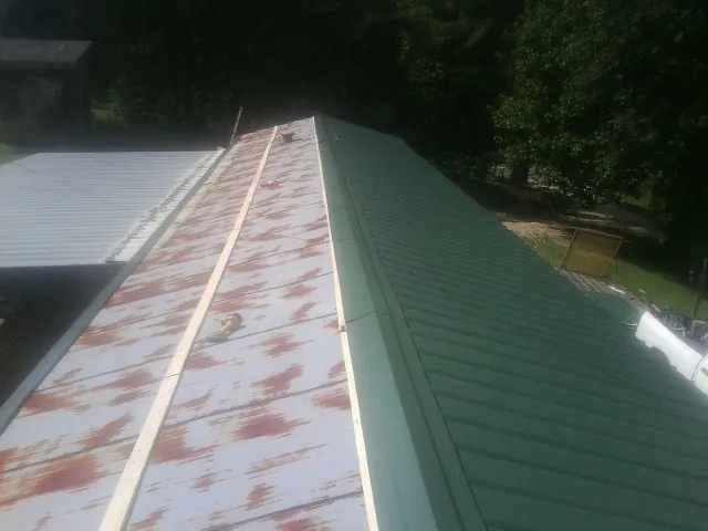 Old rusted panels beside newly installed green metal roofing — Wind Damage Roof Repair by Roofing Brothers in Arlington
